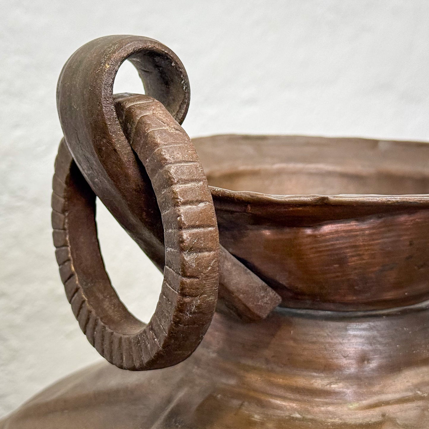 Close-up of a wooden bowl with a handle on a textured surface