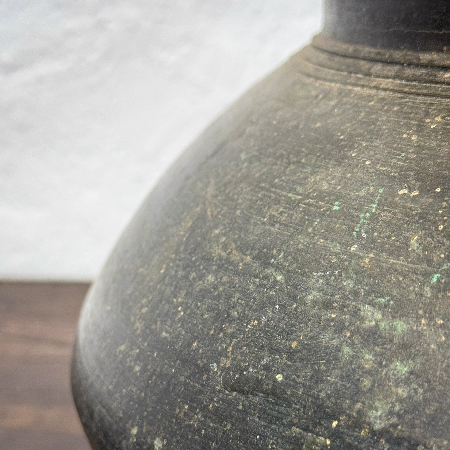 Close-up of a textured black ceramic vase against a neutral background