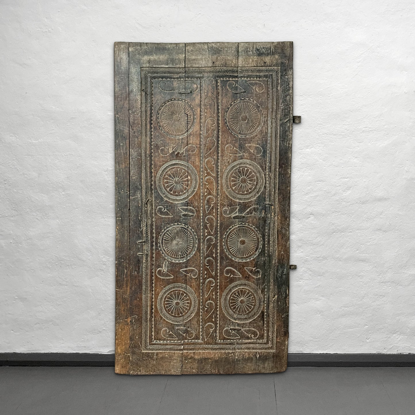 Decorative wooden panel with intricate carvings on a white wall.