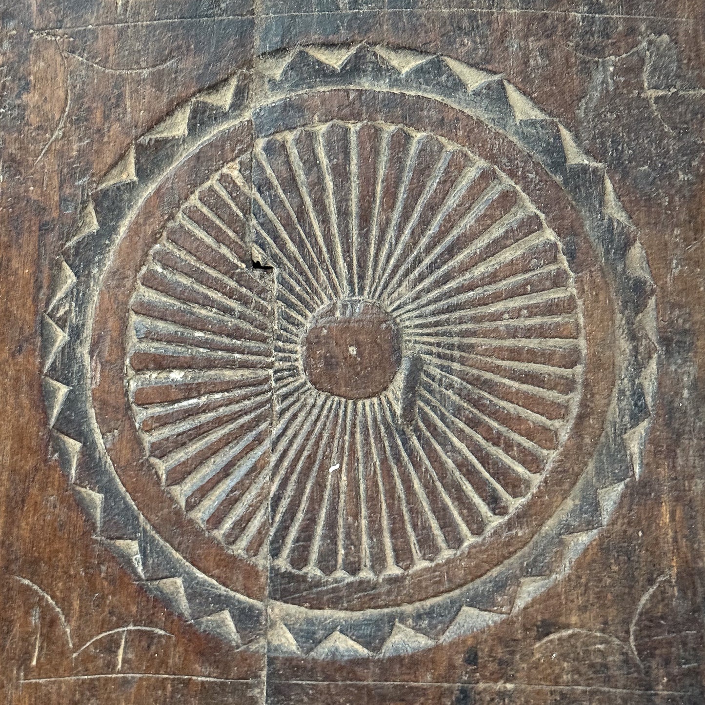 Decorative stone pattern with concentric circles and geometric design on a textured surface