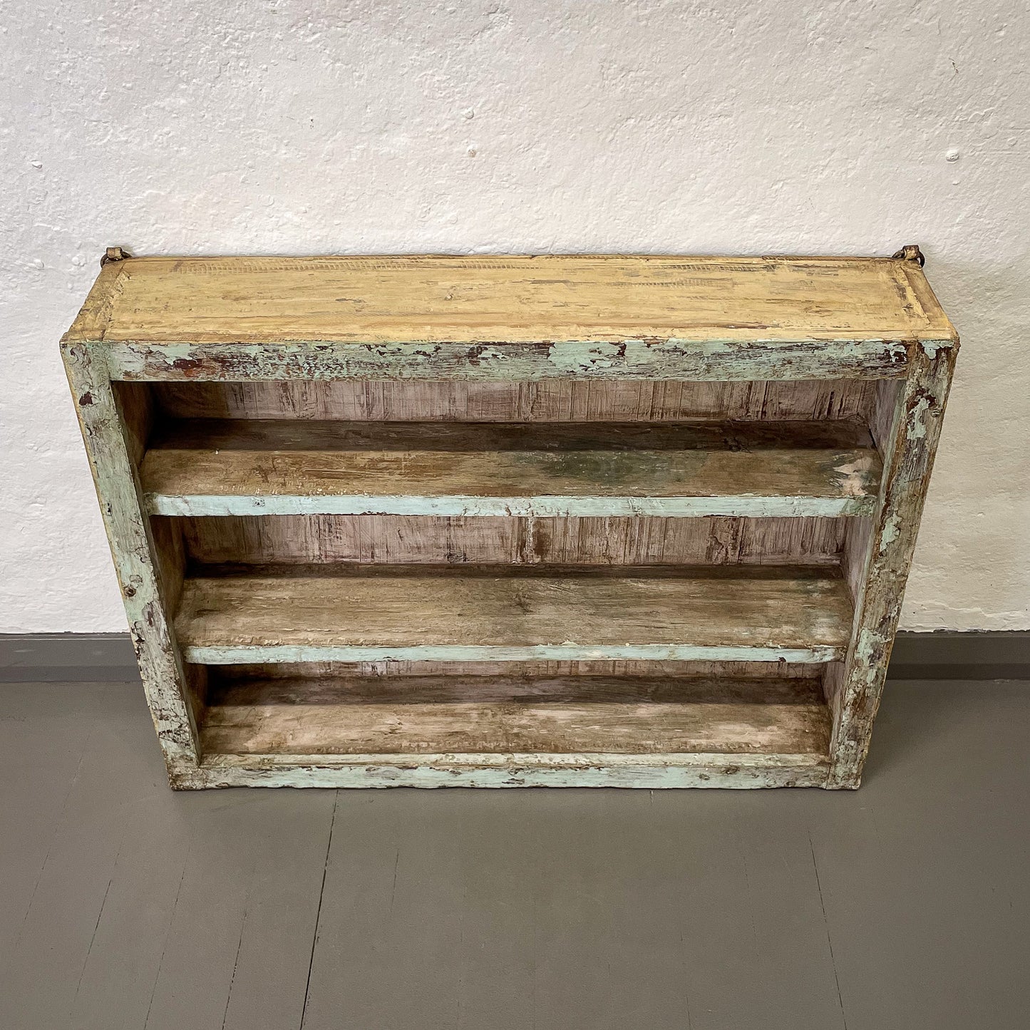 Wooden shelf with a distressed finish on a plain background