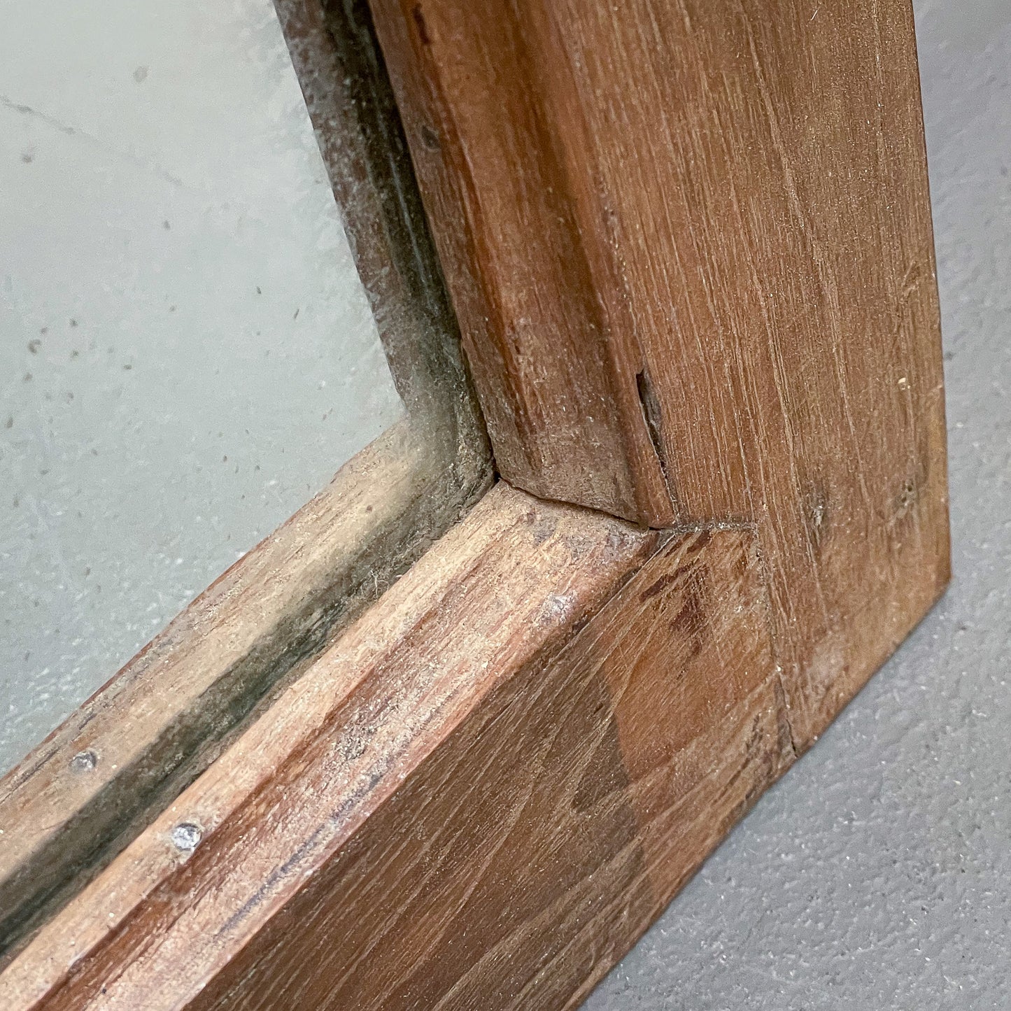 Close-up of wooden window frame corner on a gray background