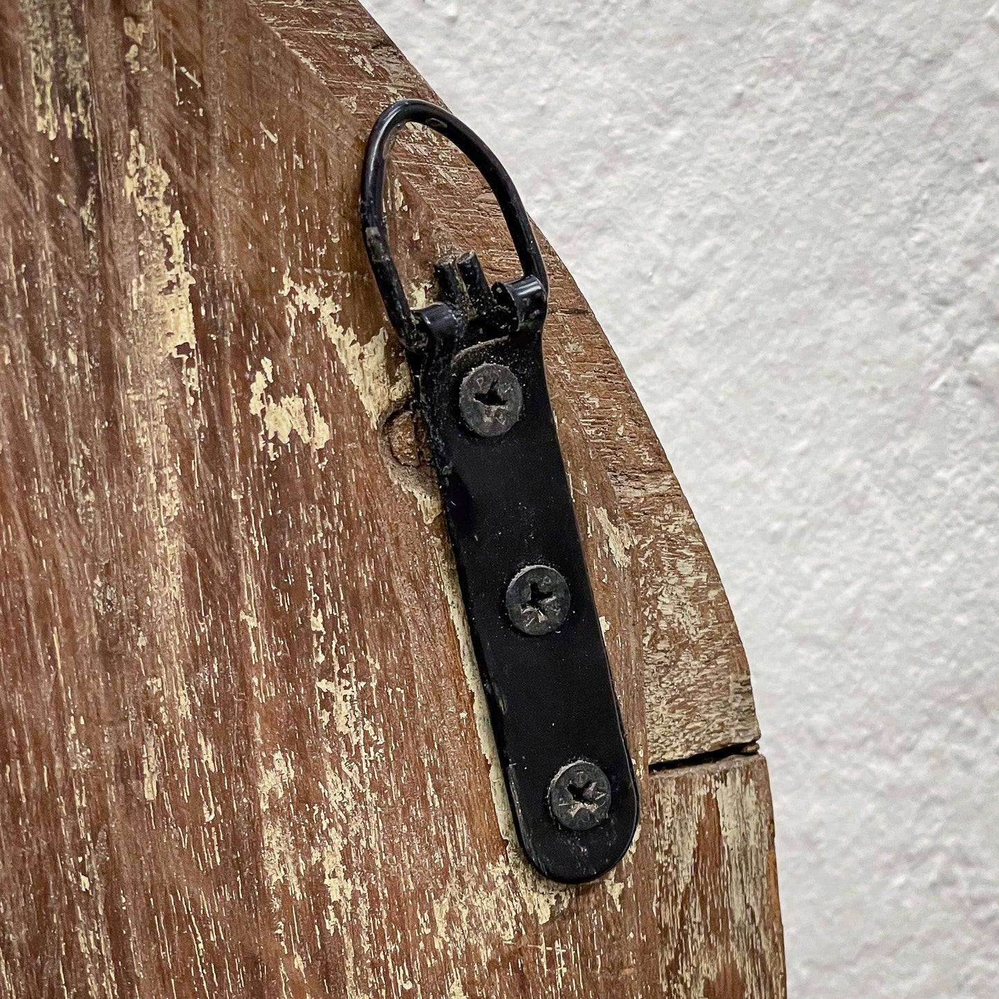 Black metal strap with screws attached to a wooden surface