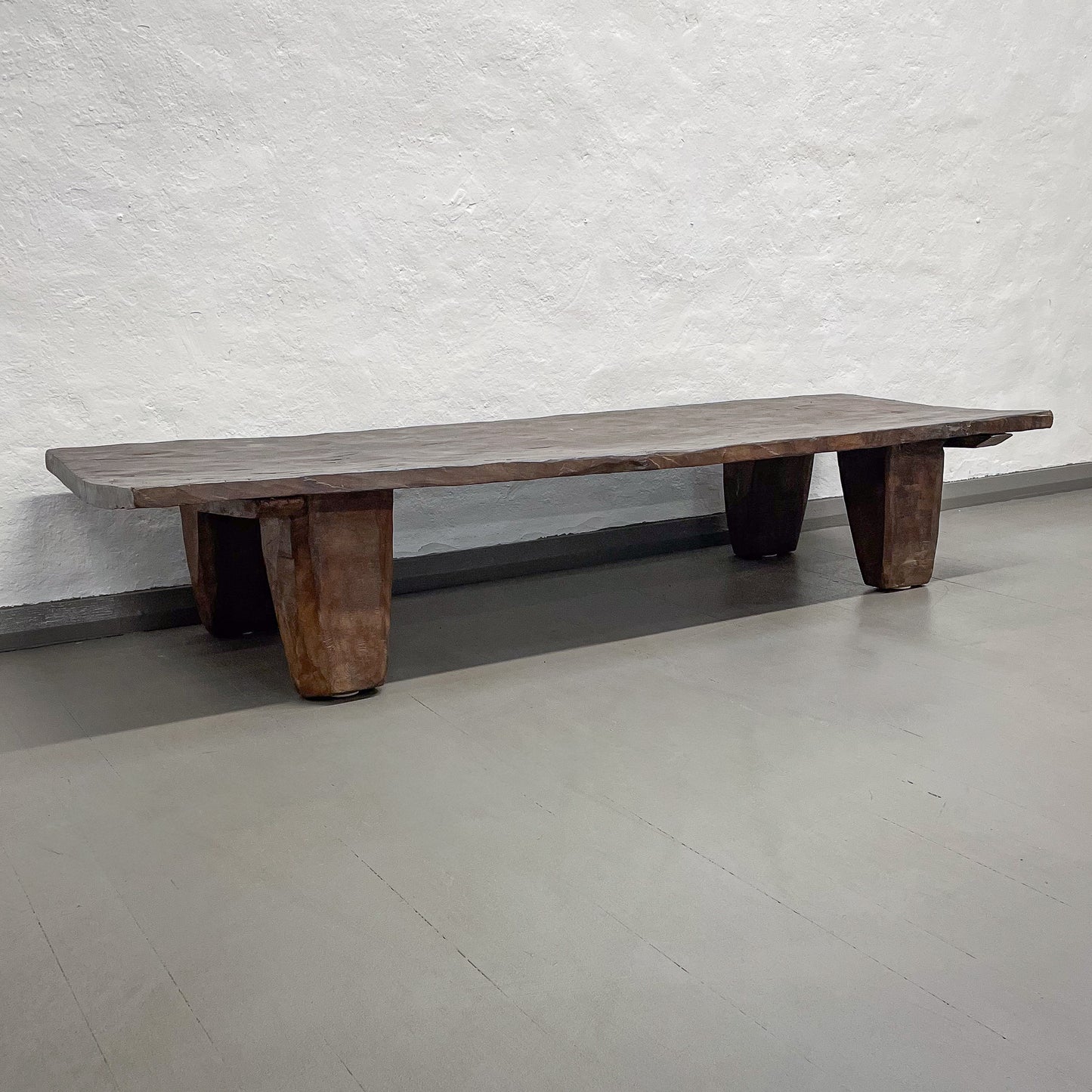 Wooden bench against a textured white wall