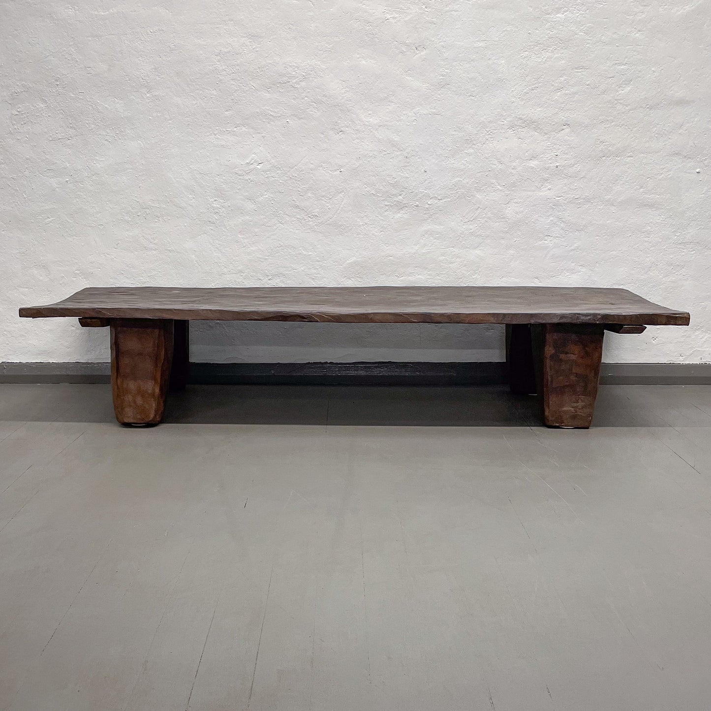 Wooden bench against a textured white wall