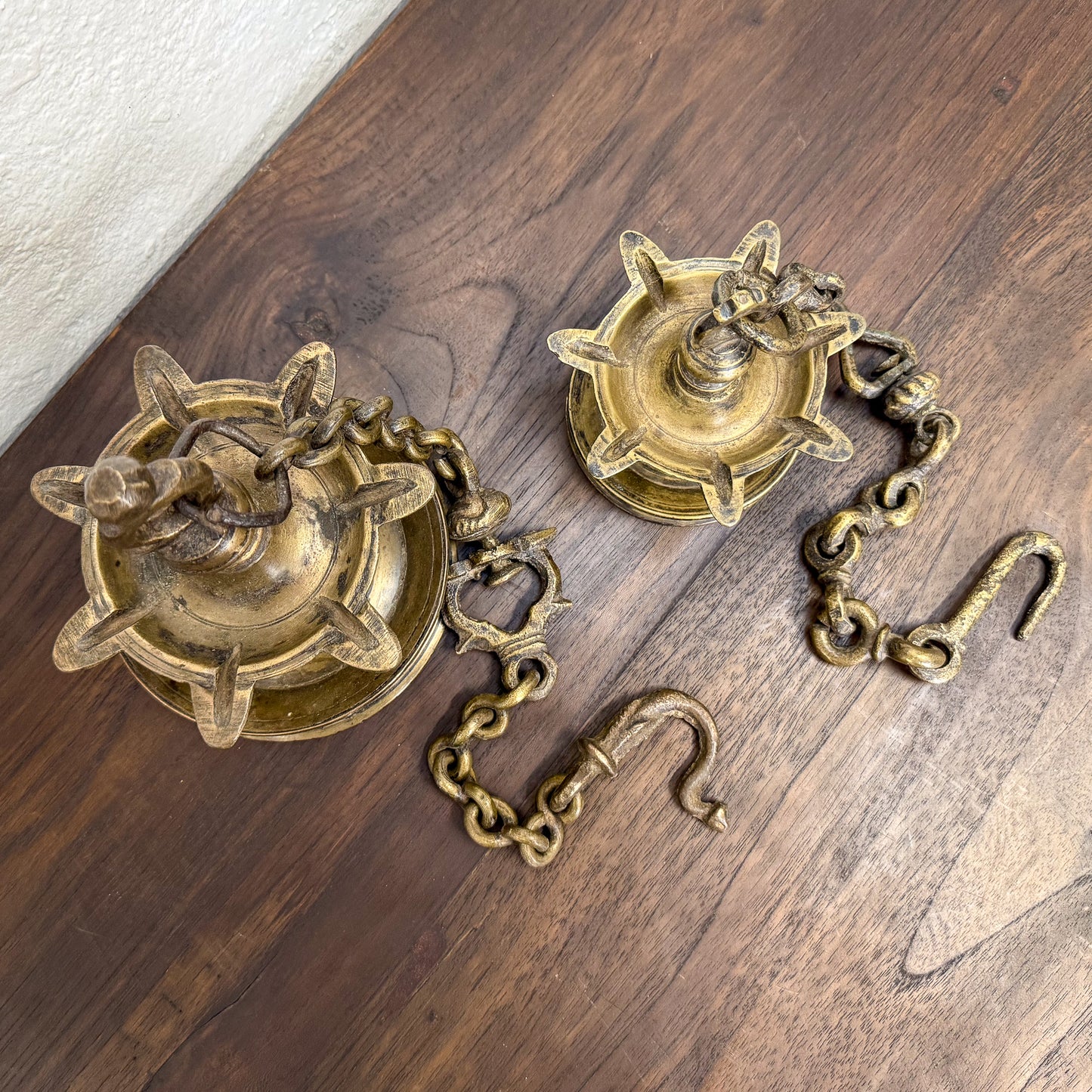 Two brass wall sconces with chains on a wooden surface