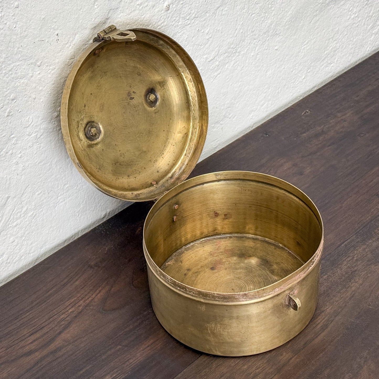 Brass container with lid on a wooden surface