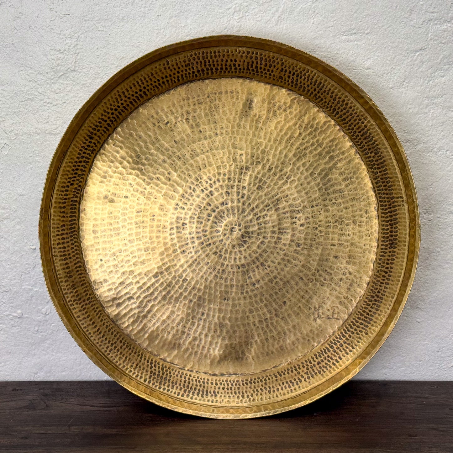 Gold decorative plate with textured surface on a white wall background