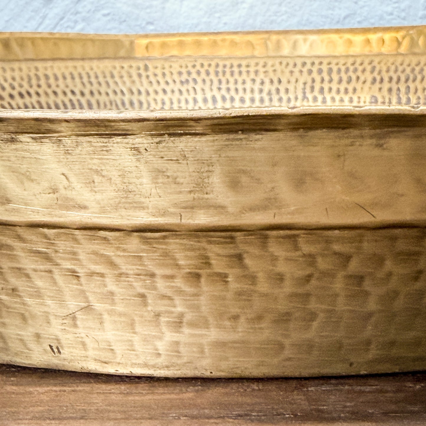 Close-up of a textured wooden box on a wooden surface with a light blue fabric background.