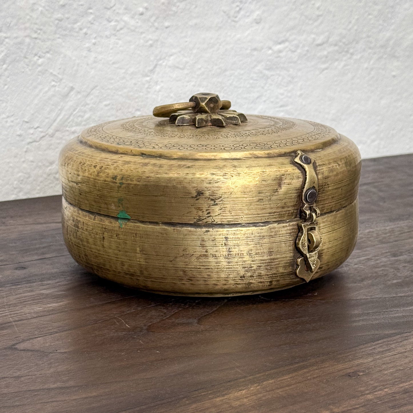 Brass decorative box with intricate designs on a wooden surface