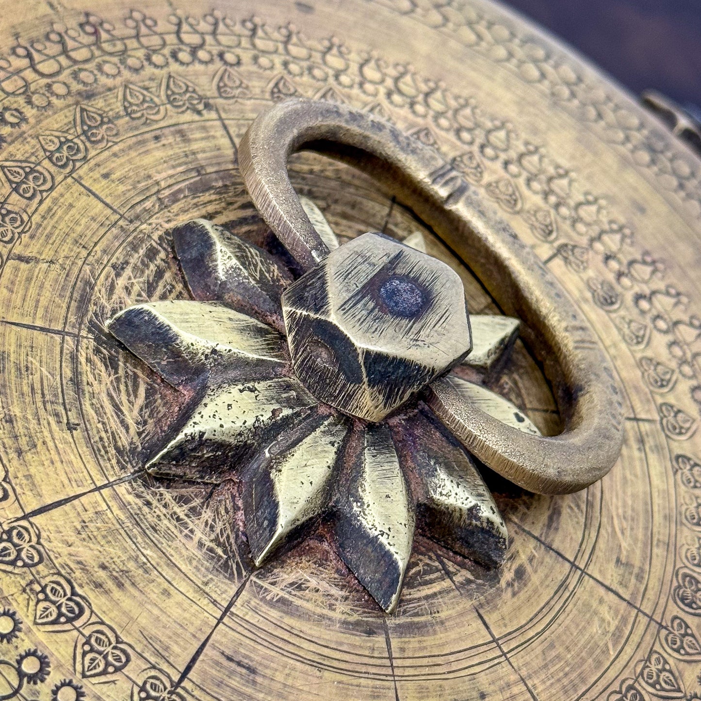 Decorative metal handle on a wooden surface with intricate carvings
