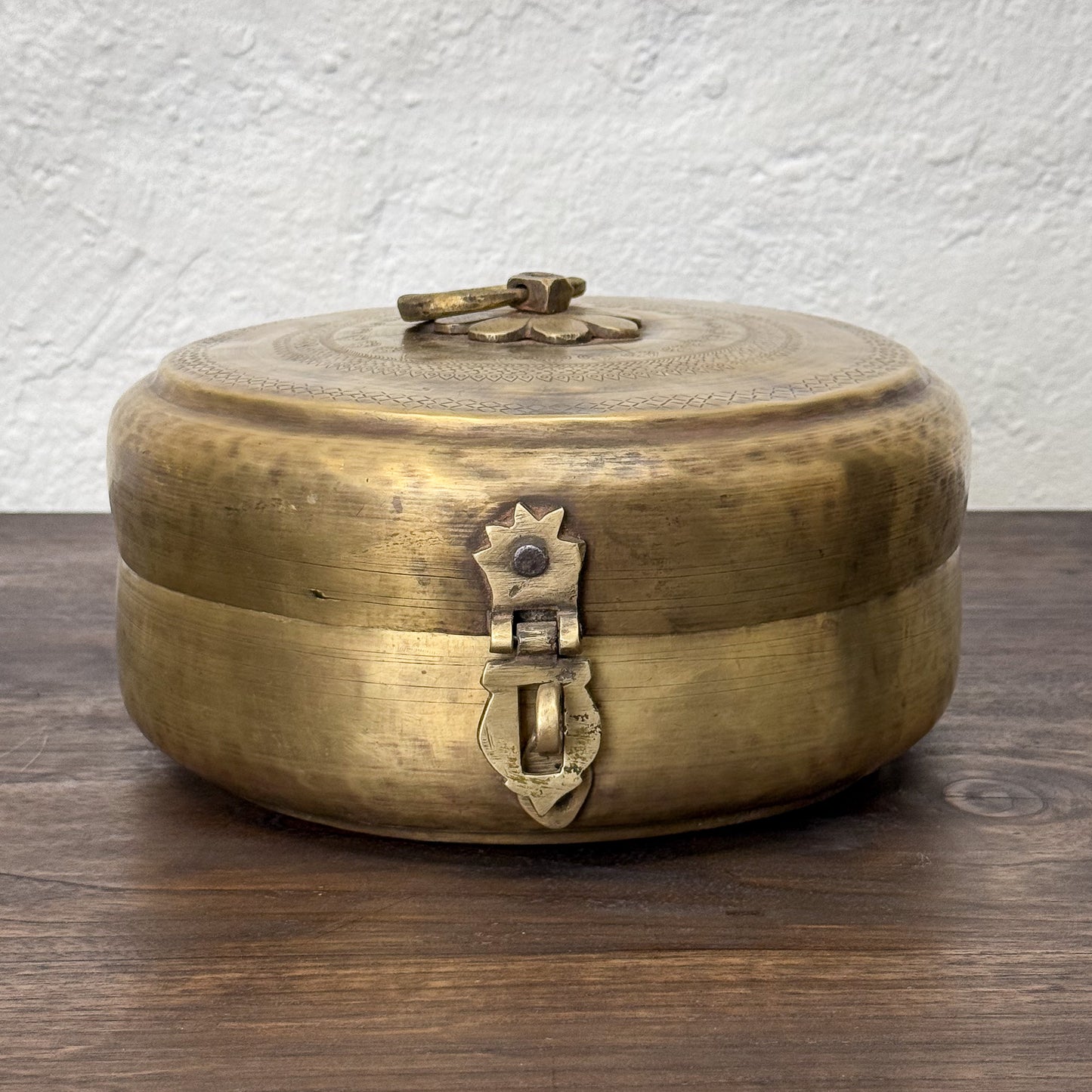 Brass box with intricate designs on a wooden surface