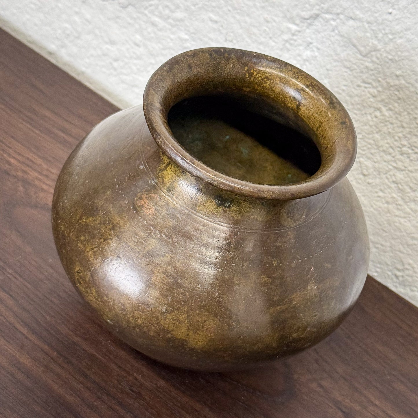 Brown ceramic pot on a wooden surface with a white wall background