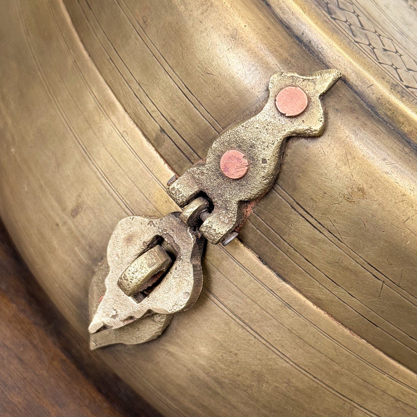 Close-up of a decorative metal hinge on a wooden surface