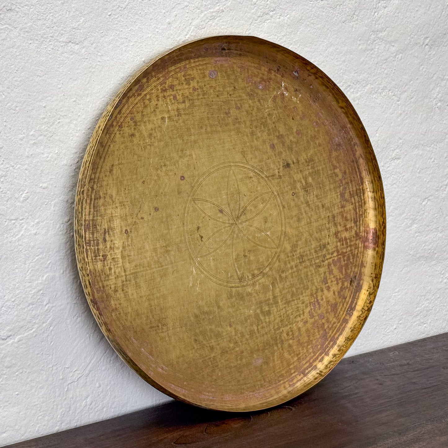 Round wooden tray with engraved design on a white wall background