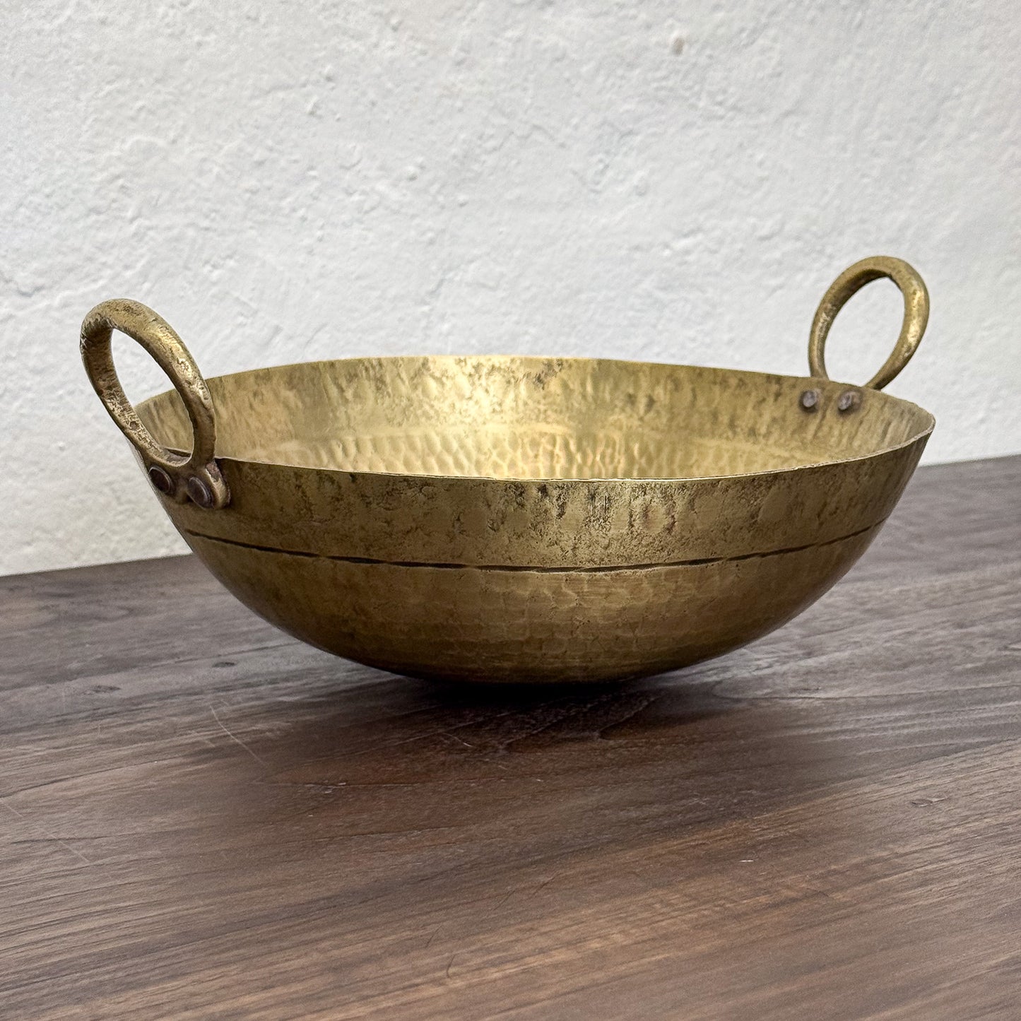 Brass bowl with handles on a wooden surface