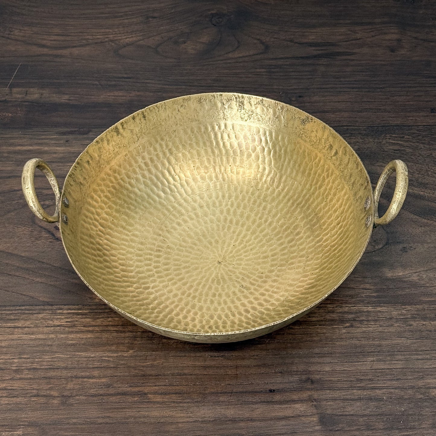 Gold decorative bowl with handles on a wooden surface