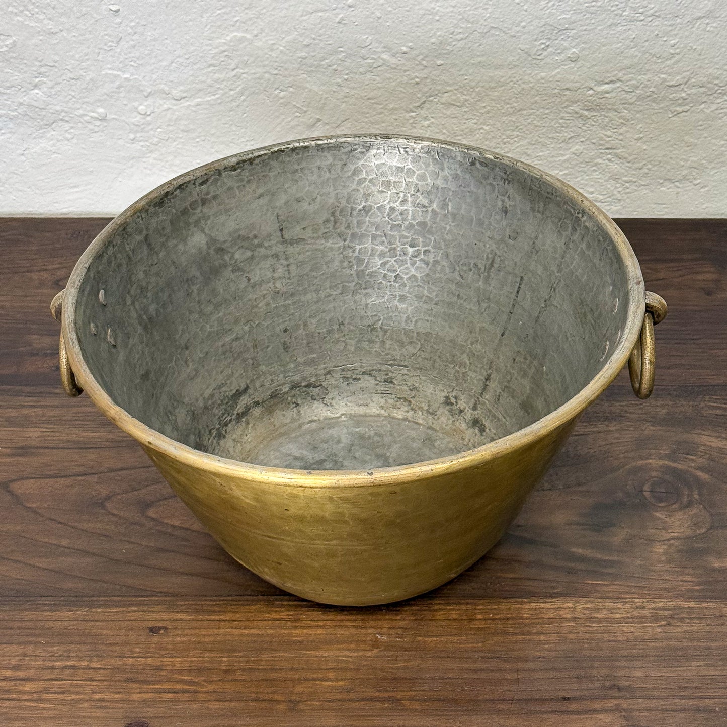 Vintage metal bucket on a wooden surface with a white wall background