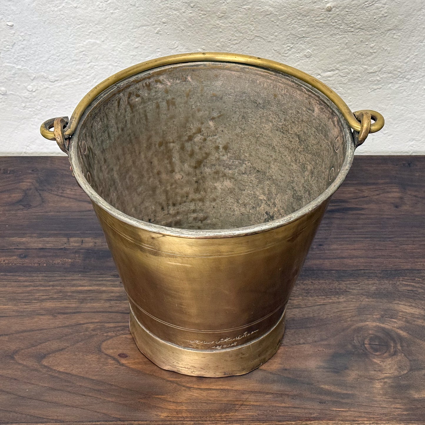 Brass bucket with handles on a wooden surface