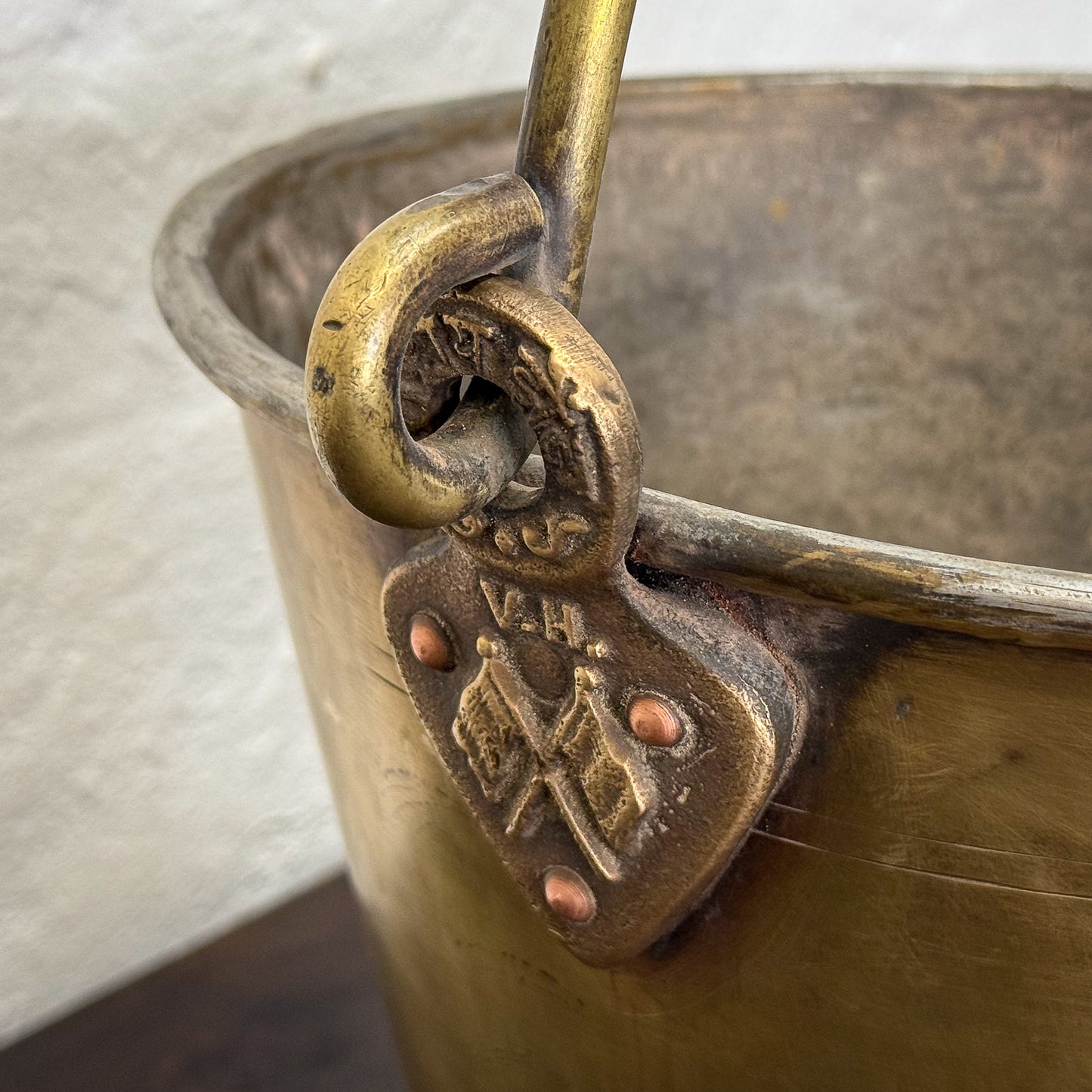 Close-up of a brass handle on a metal bucket with visible branding.