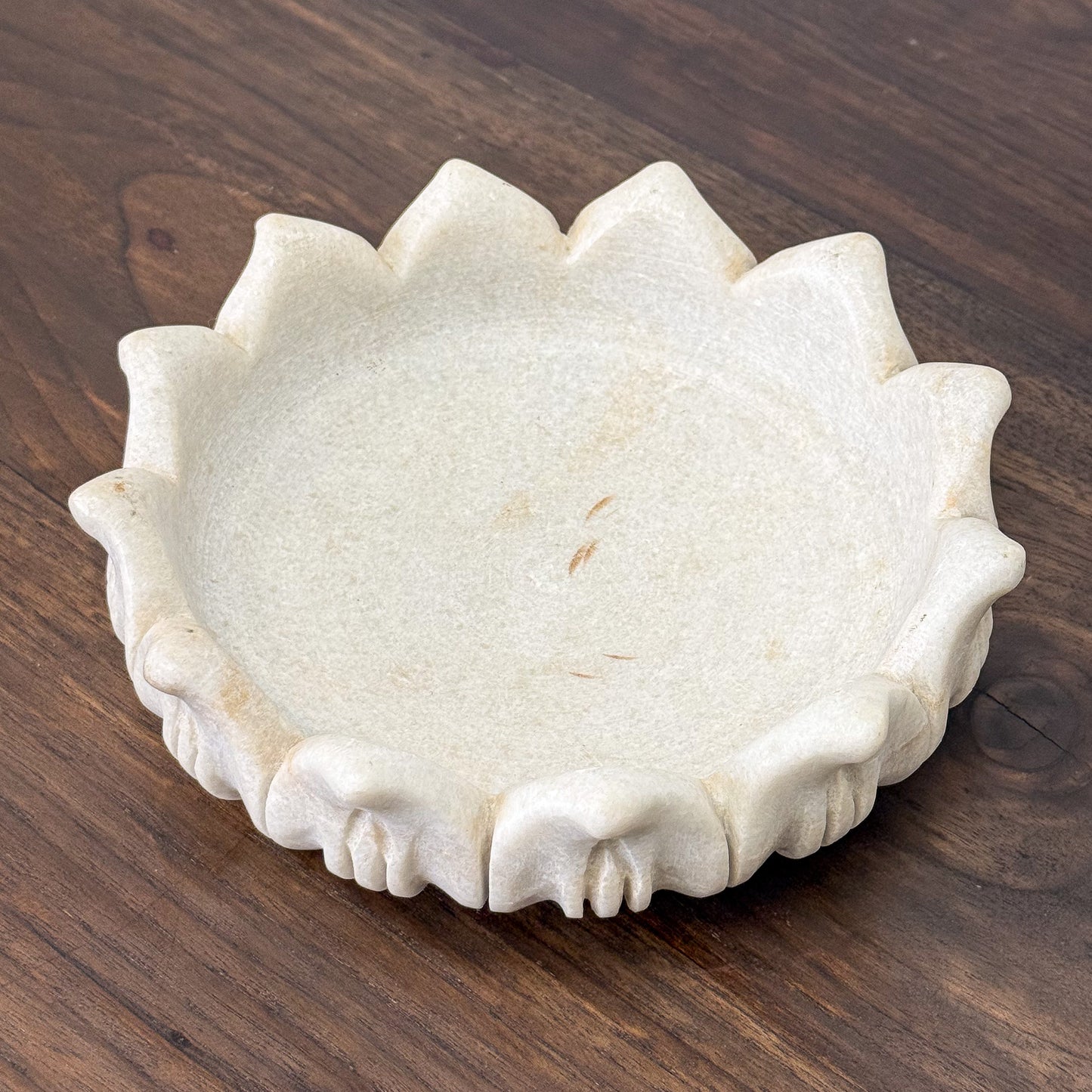 Decorative stone bowl with scalloped edge on a wooden surface