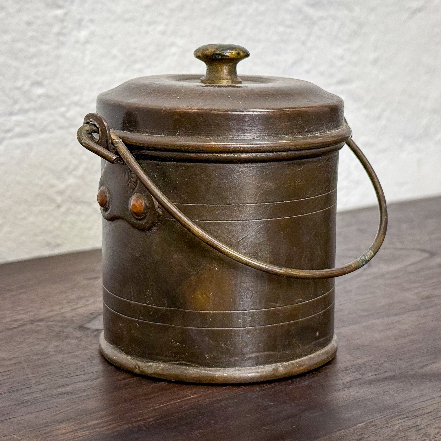 Vintage metal bucket with a lid on a wooden surface