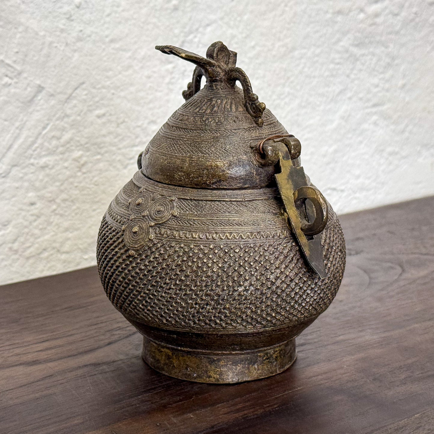 Decorative metal container with intricate designs on a wooden surface
