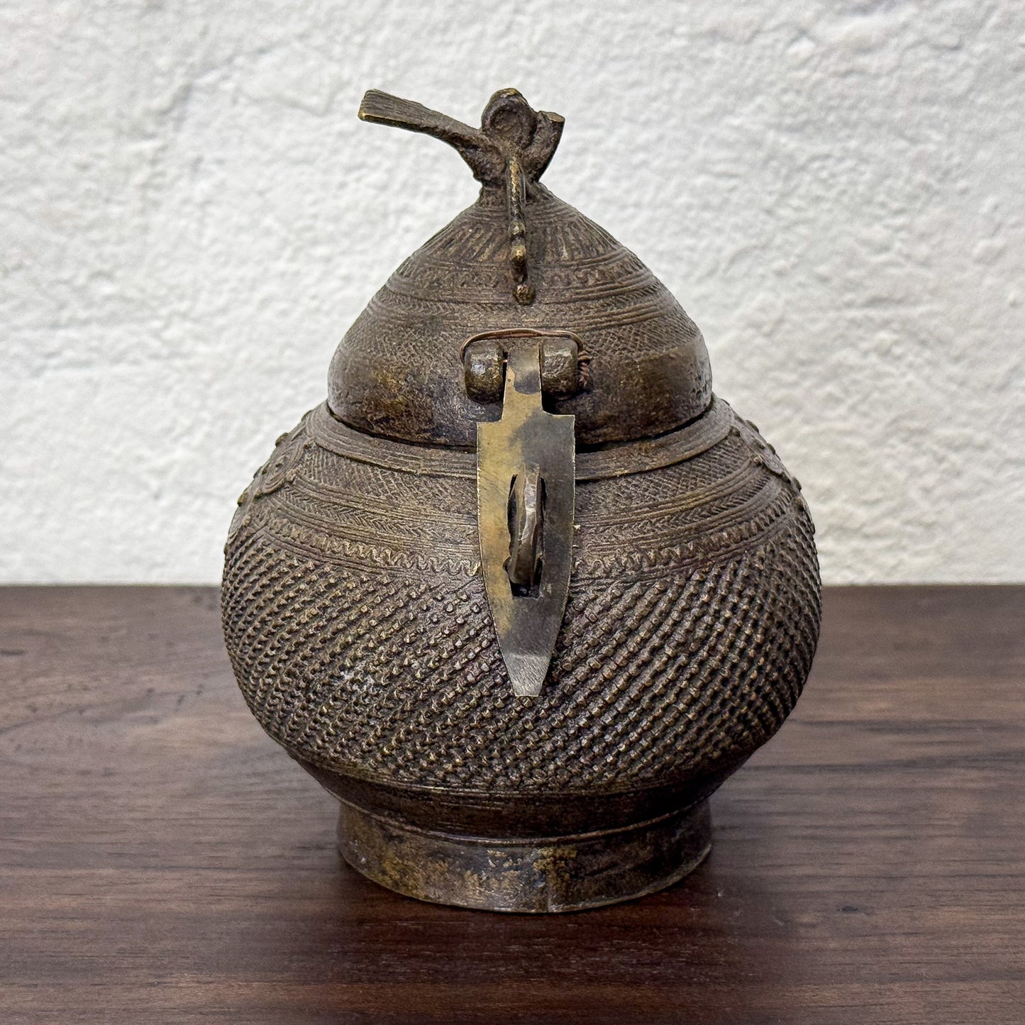 Decorative bronze teapot with intricate patterns on a wooden surface.