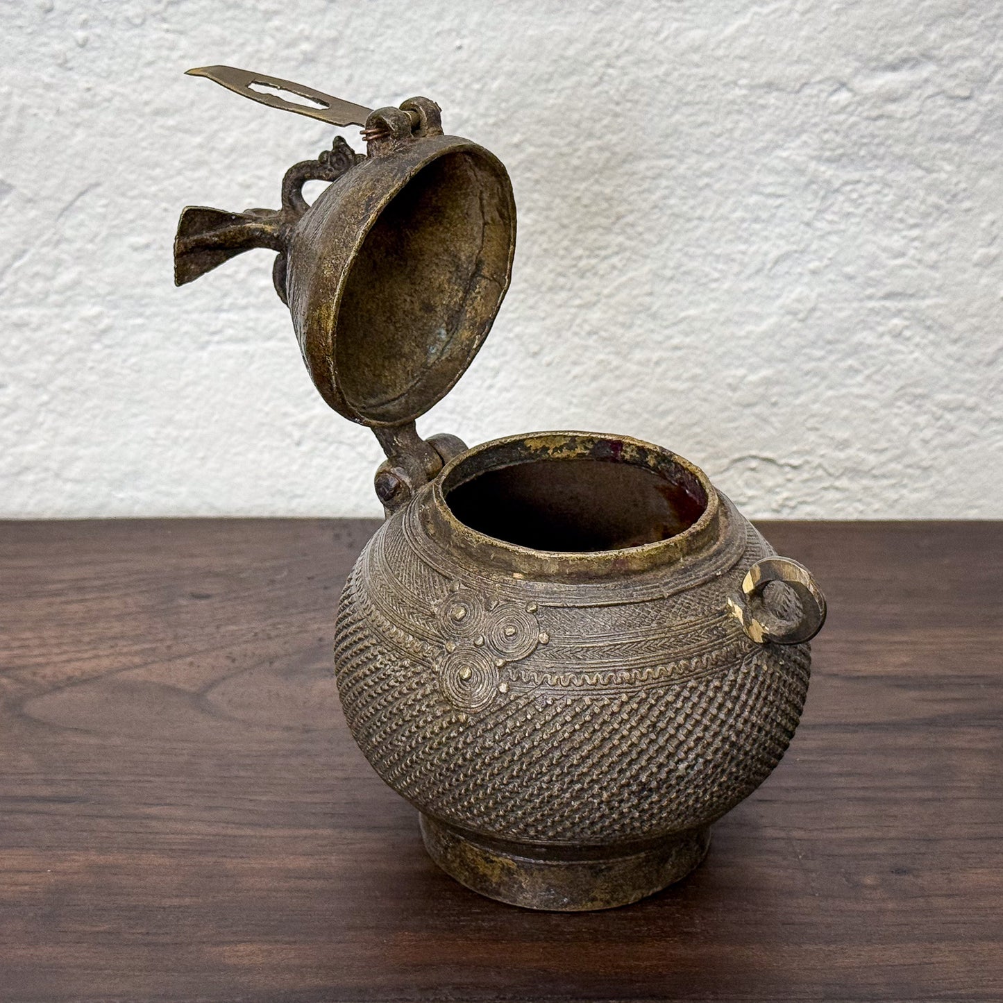 Bronze pot with lid on a wooden surface