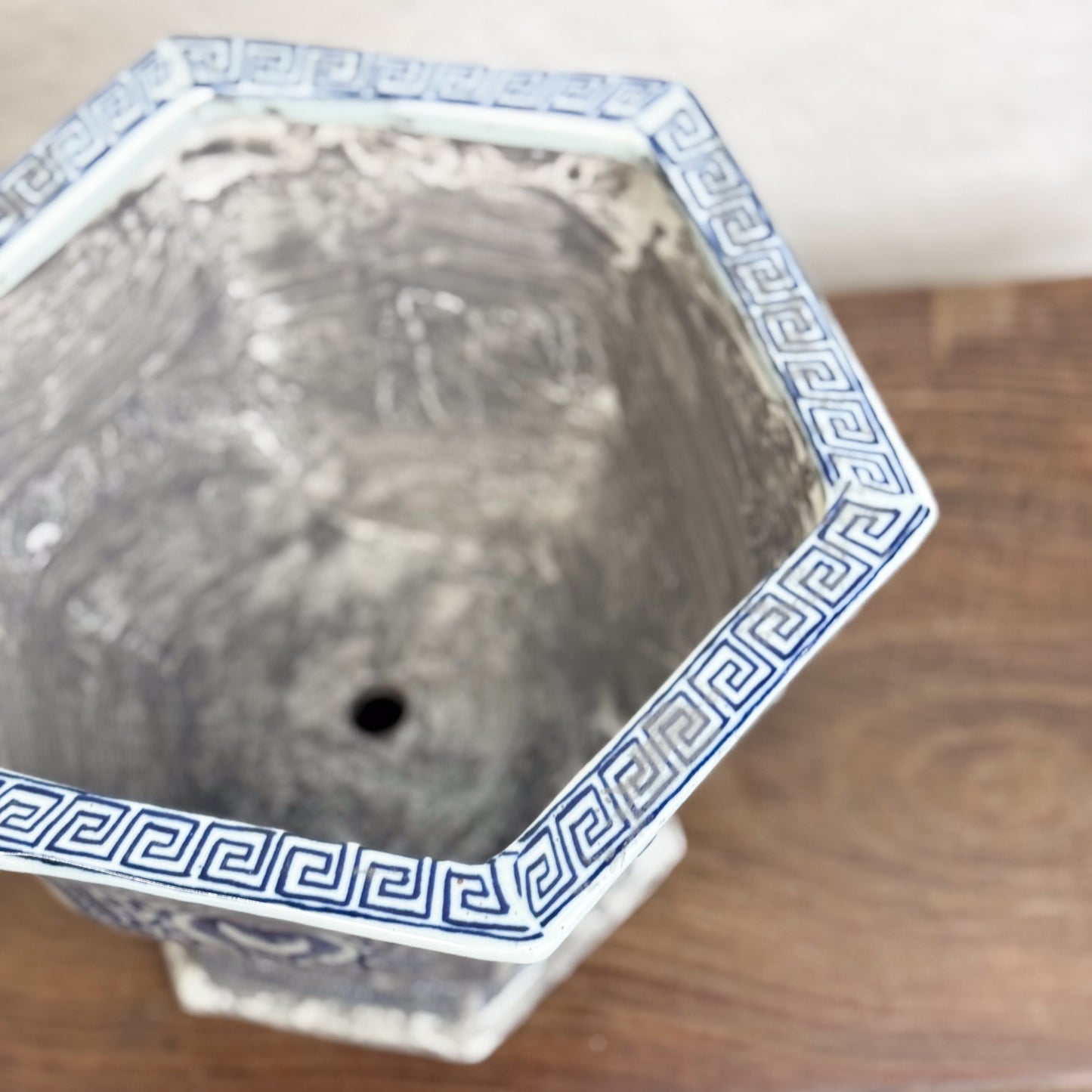 Two hexagonal porcelain planters with blue floral patterns on a wooden surface against a neutral background.