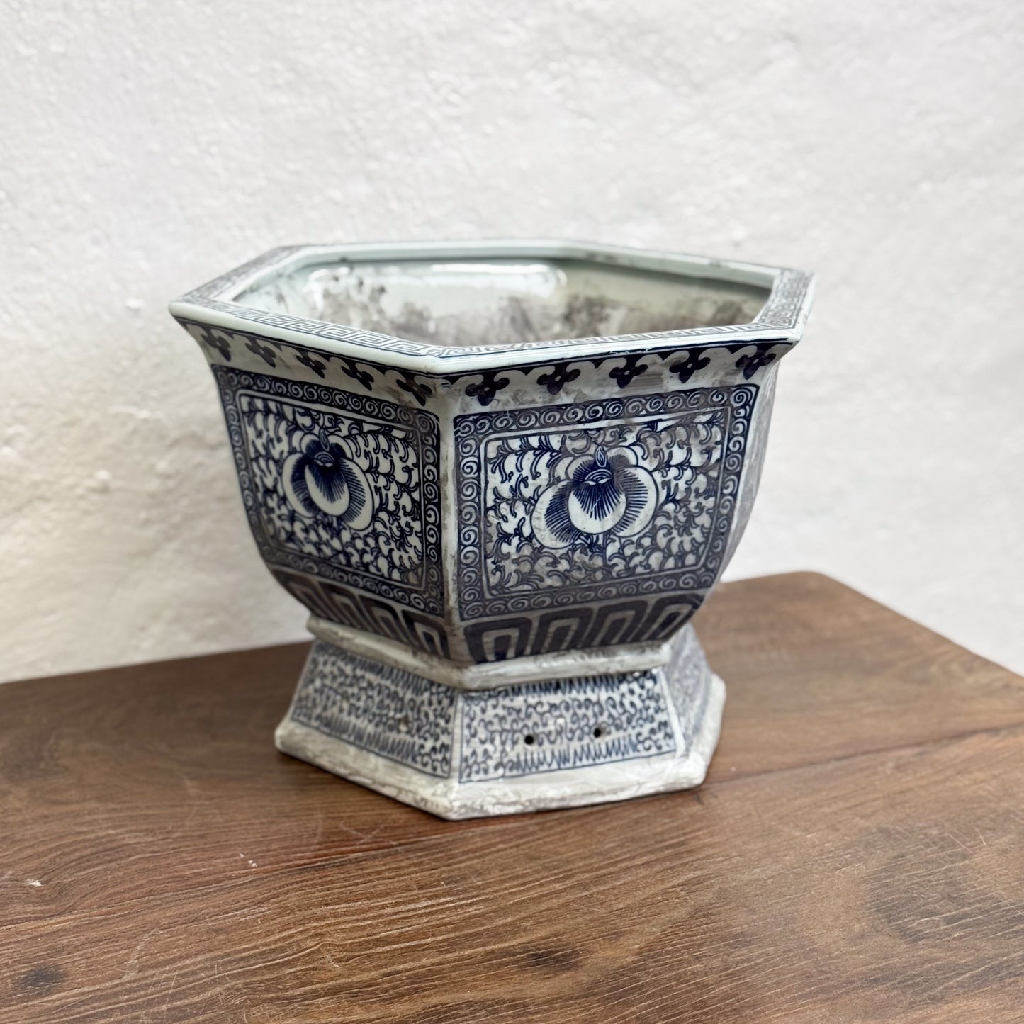 Two hexagonal porcelain planters with blue floral patterns on a wooden surface against a neutral background.