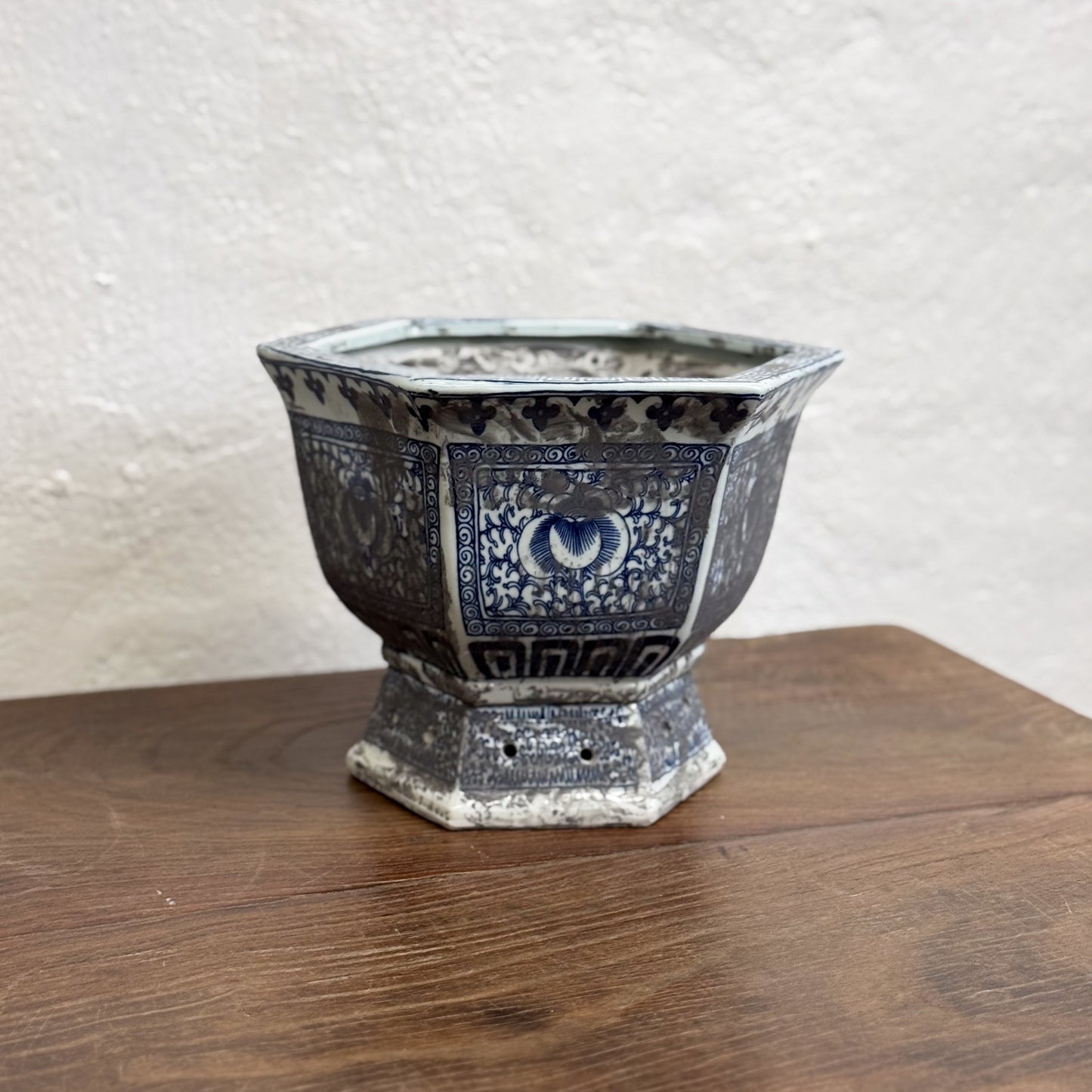 Two hexagonal porcelain planters with blue floral patterns on a wooden surface against a neutral background.