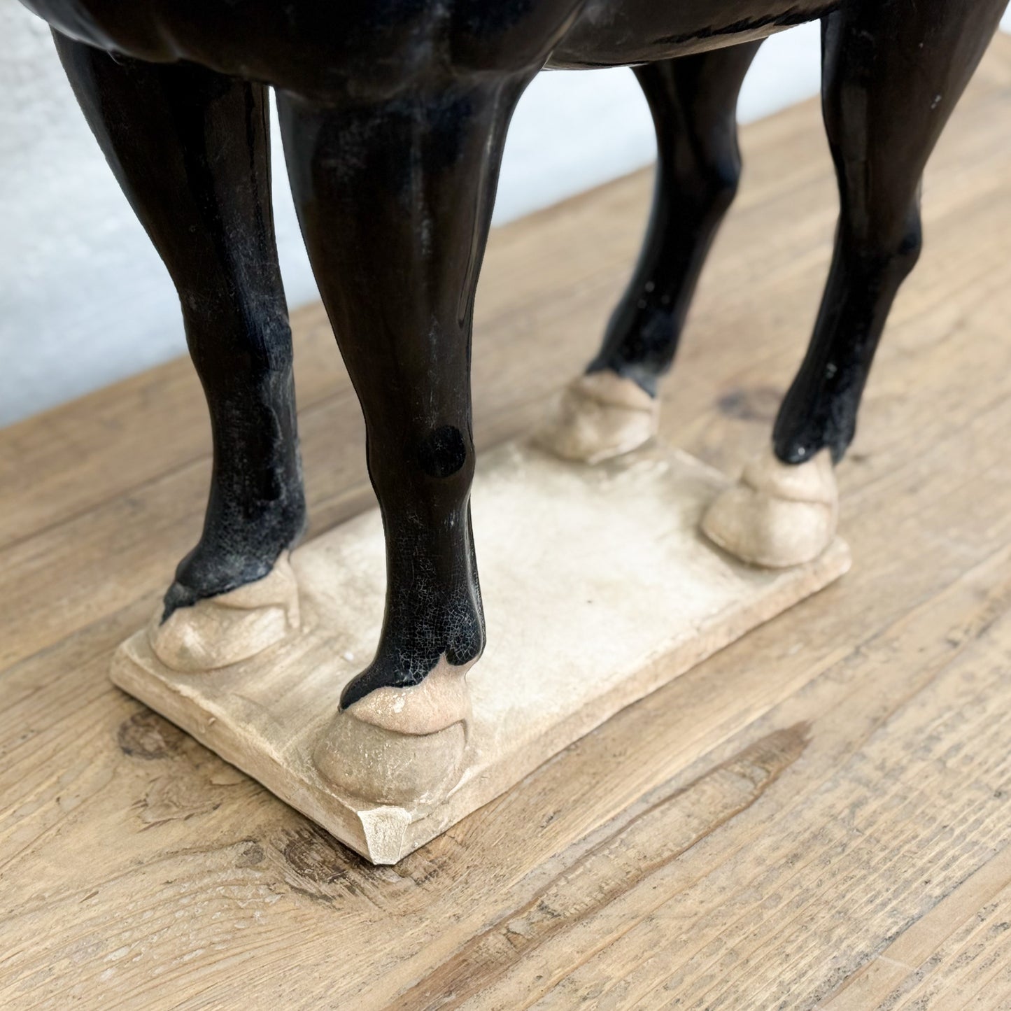 Black horse statue on a stone base on a wooden floor