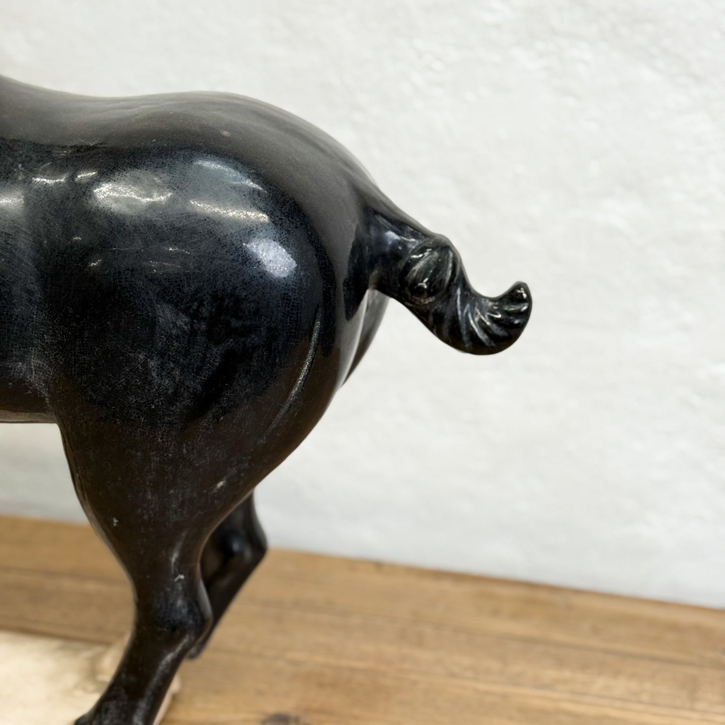 Bronze bull sculpture on a wooden base with a white textured wall background