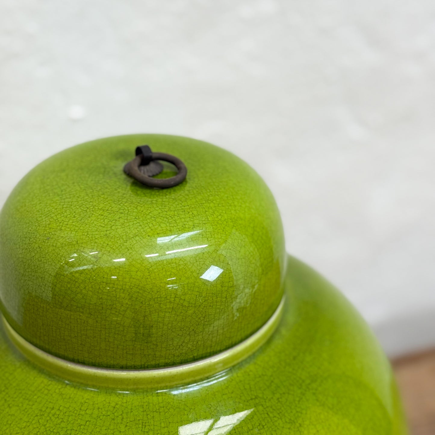 Green ceramic jar with a lid on a white background
