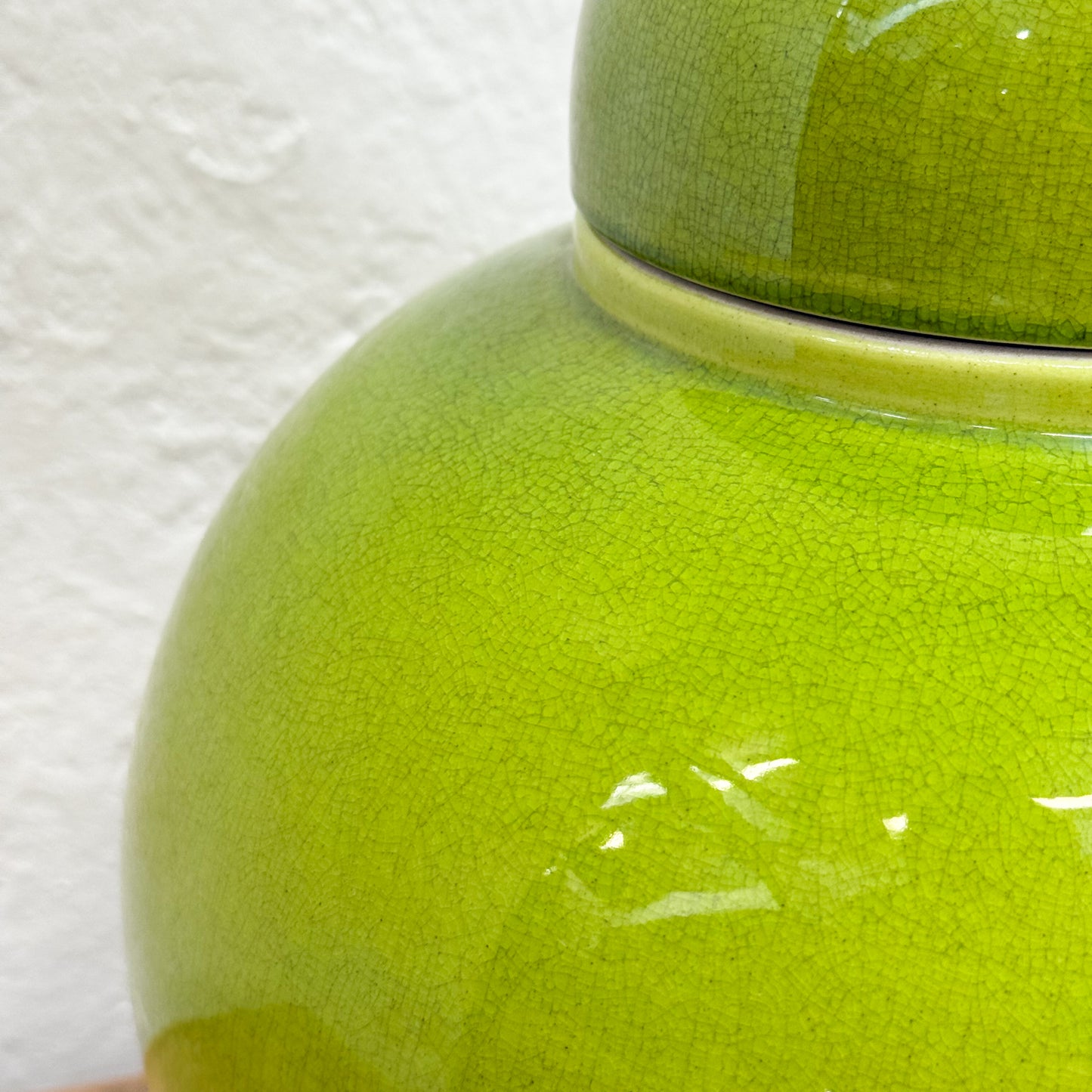 Close-up of a green ceramic jar with a textured surface on a white background