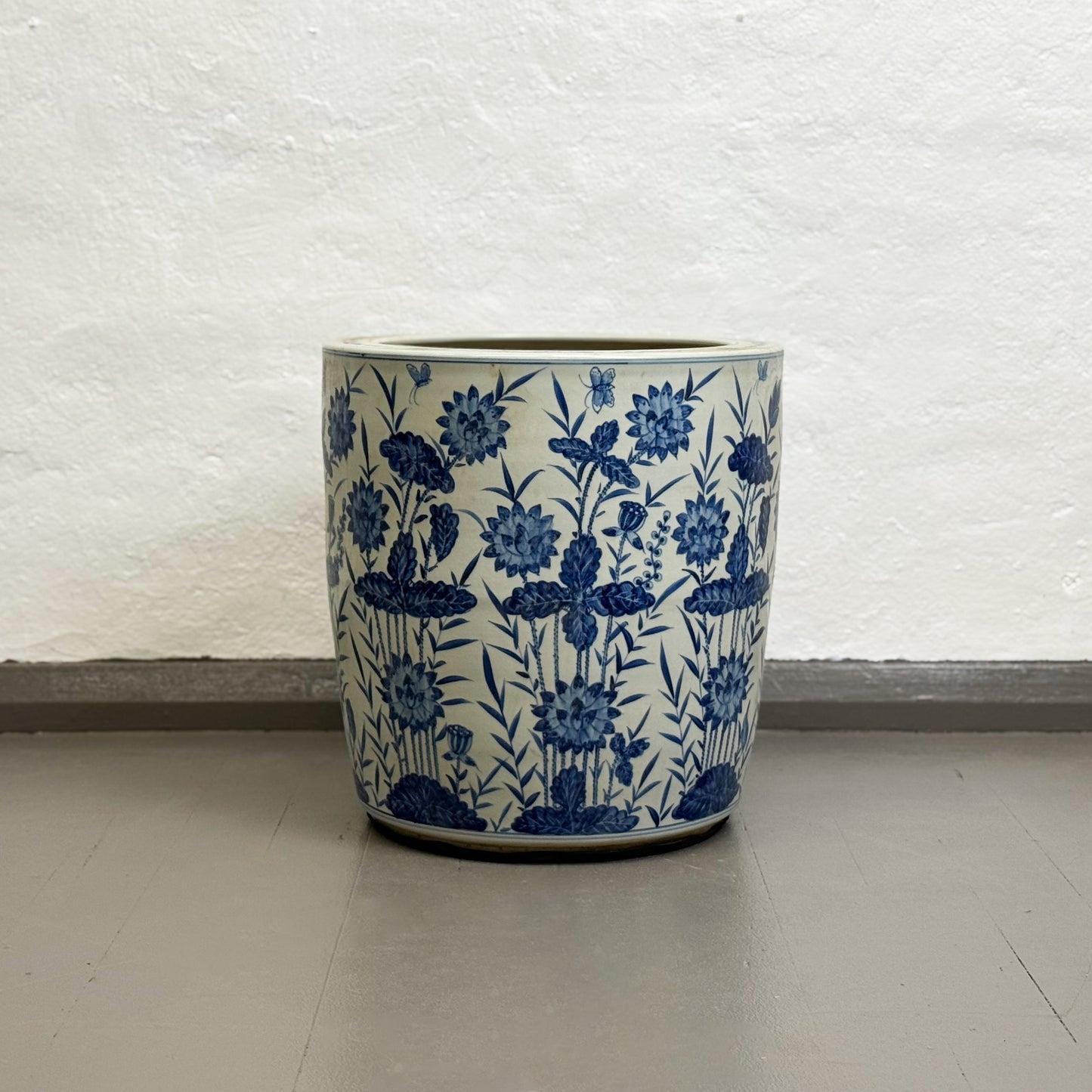 Ceramic planter with blue floral pattern on a white textured wall background