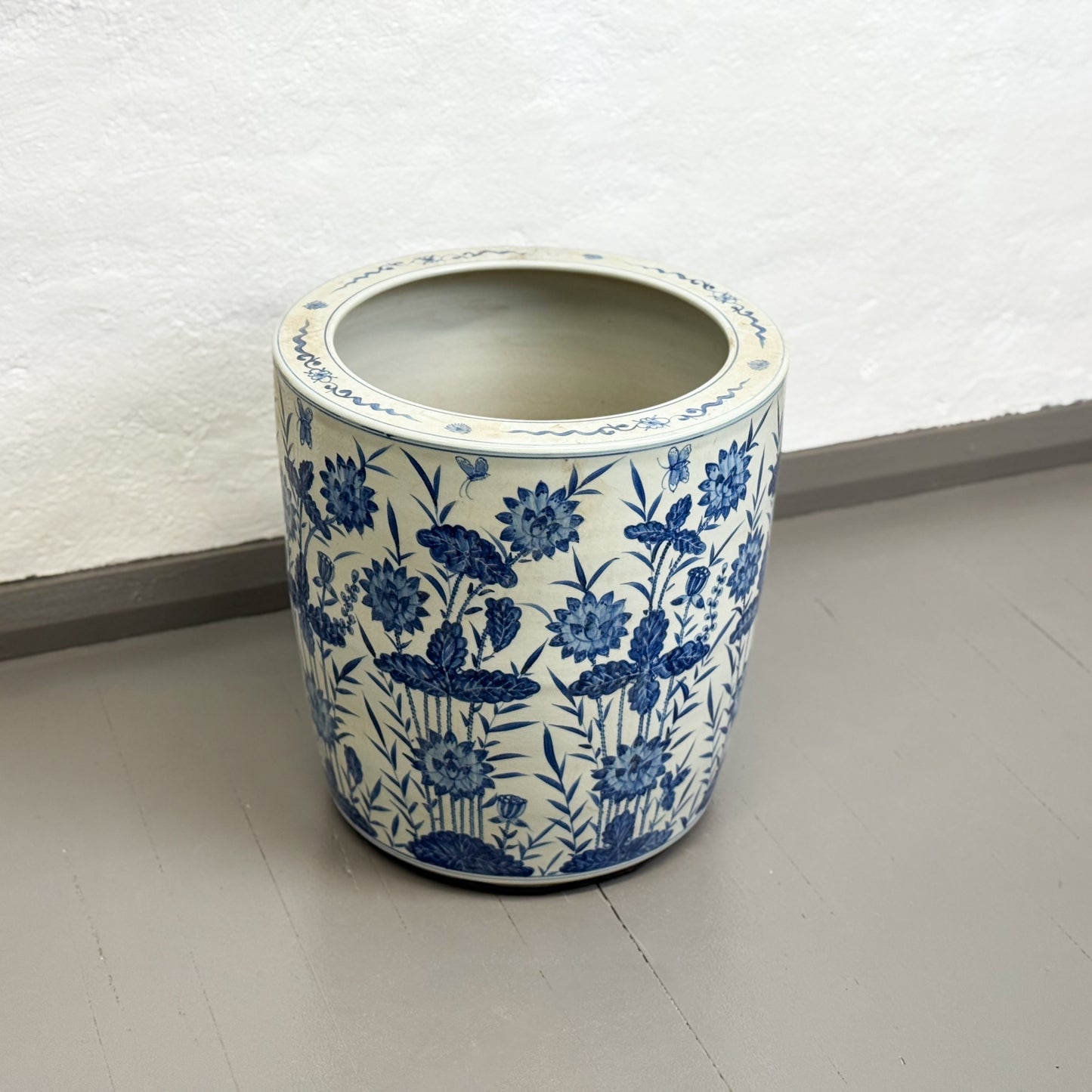 Ceramic planter with blue floral pattern on a plain floor.