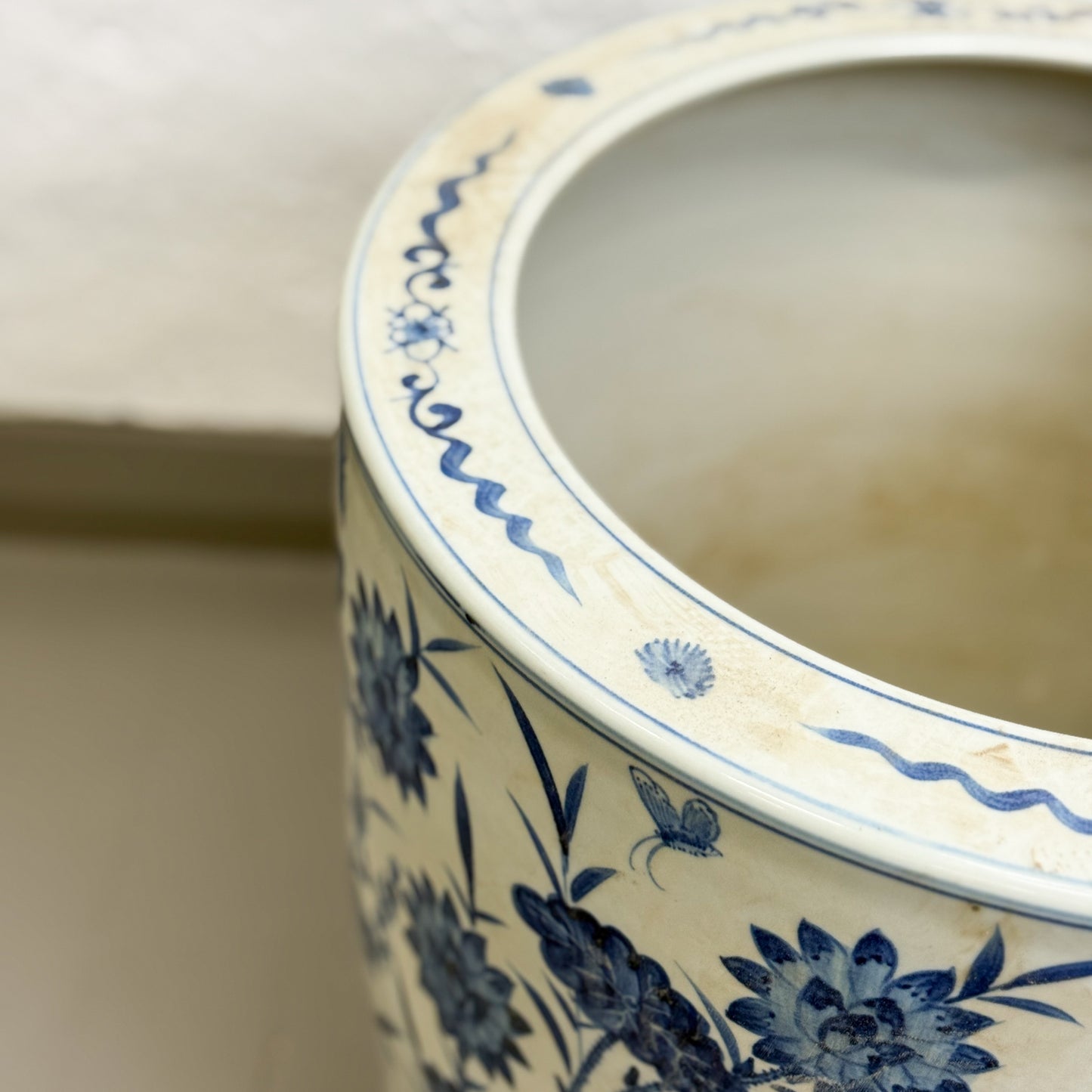 Ceramic pot with blue floral and butterfly patterns on a neutral background