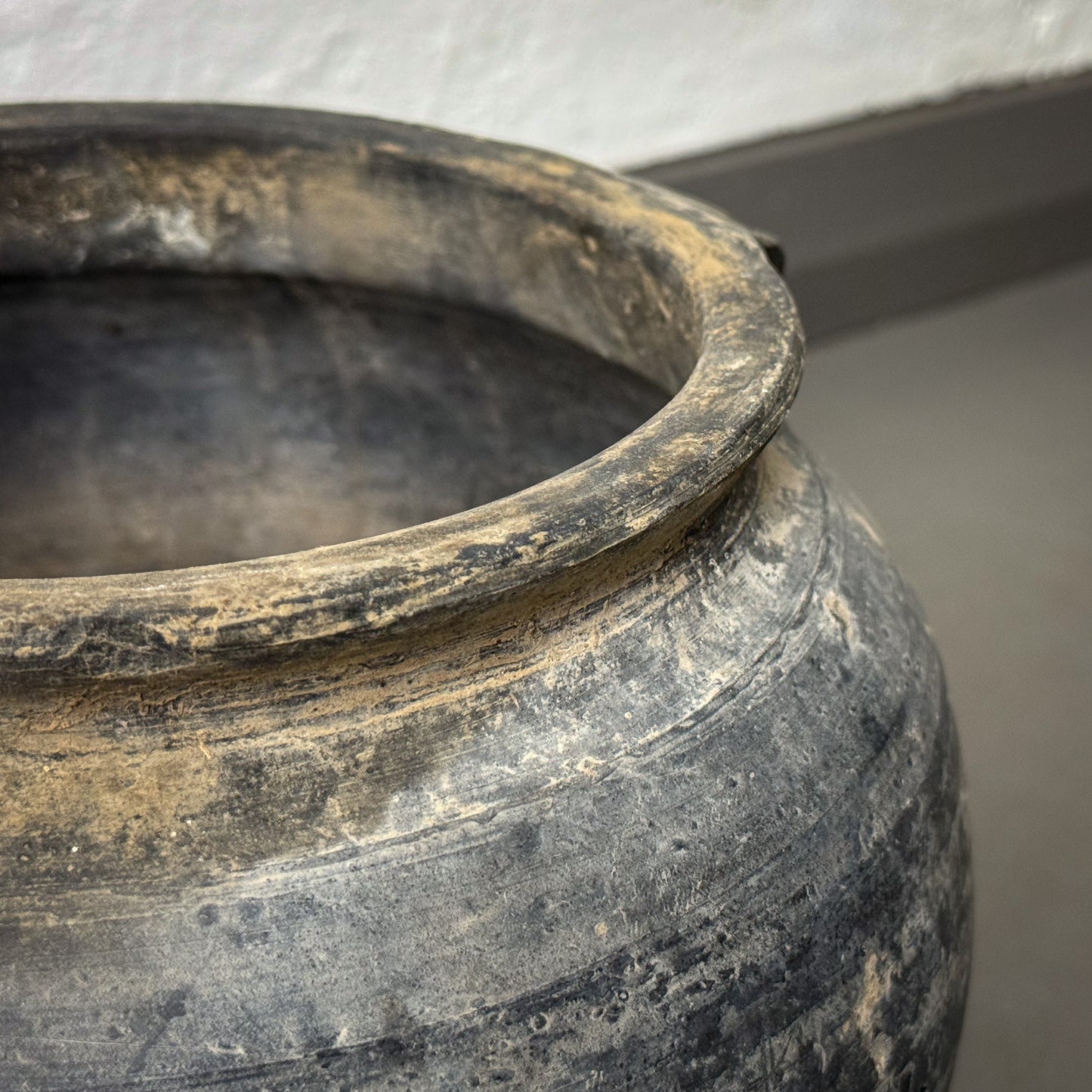 Close-up of an ancient pot with a textured surface on a neutral background