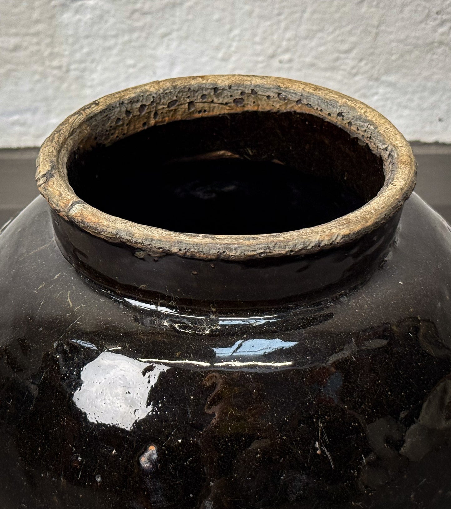 Black ceramic jar with a textured surface against a white wall