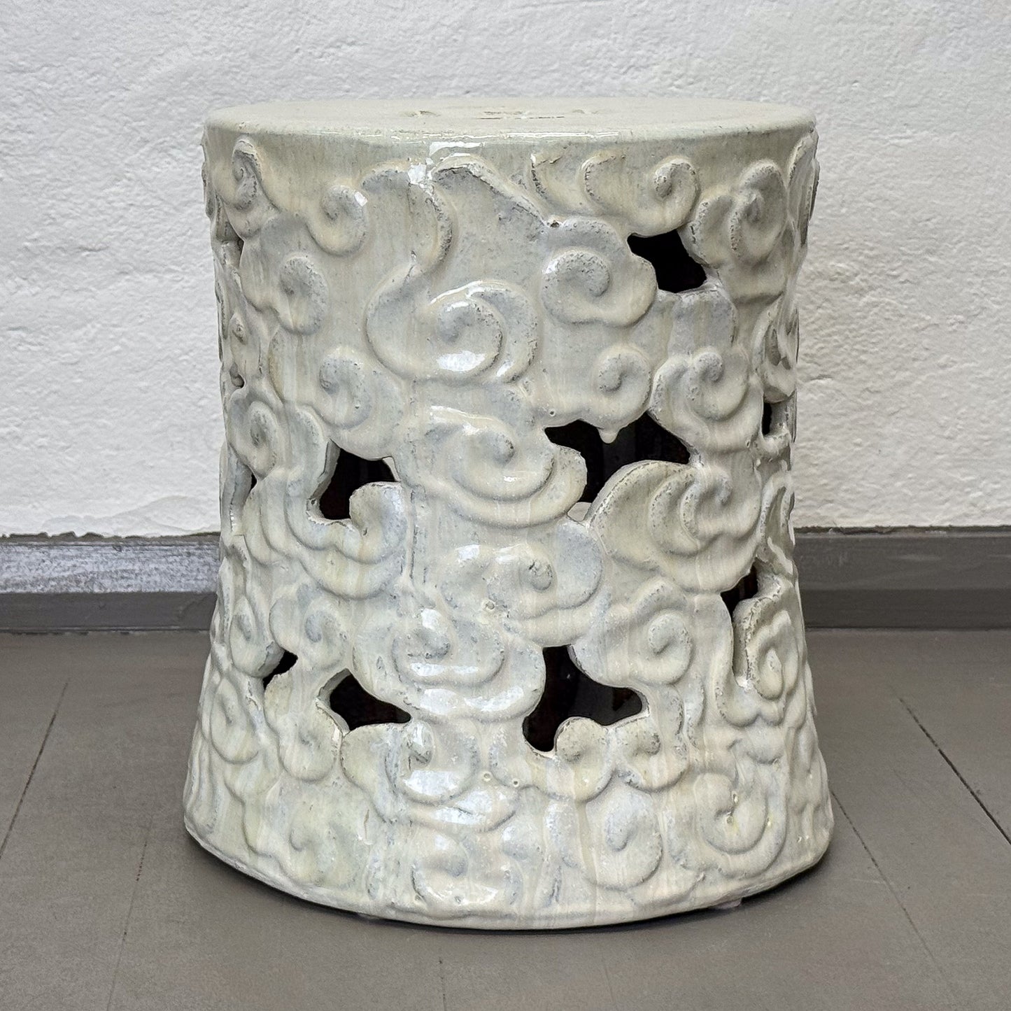 Decorative ceramic stool with cloud patterns on a plain background