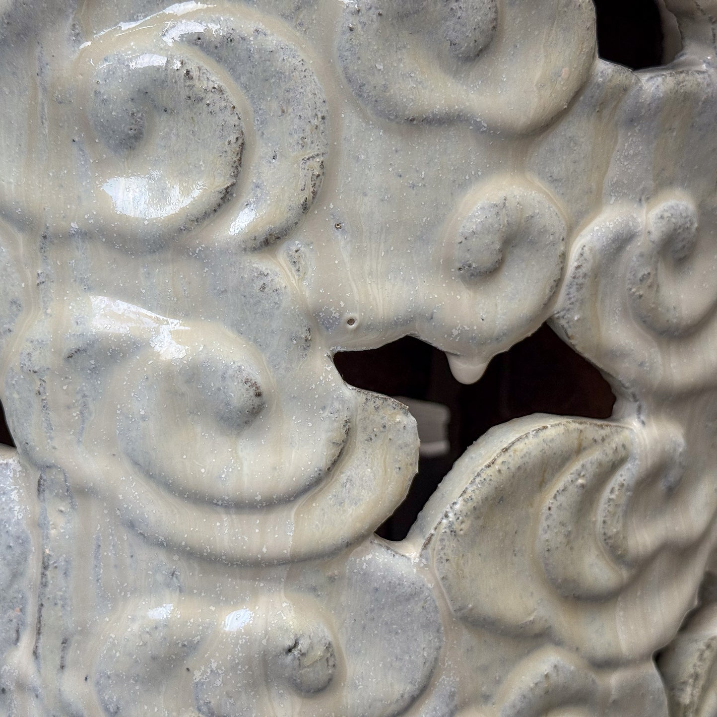 Decorative white ceramic stool with cloud patterns on a plain background