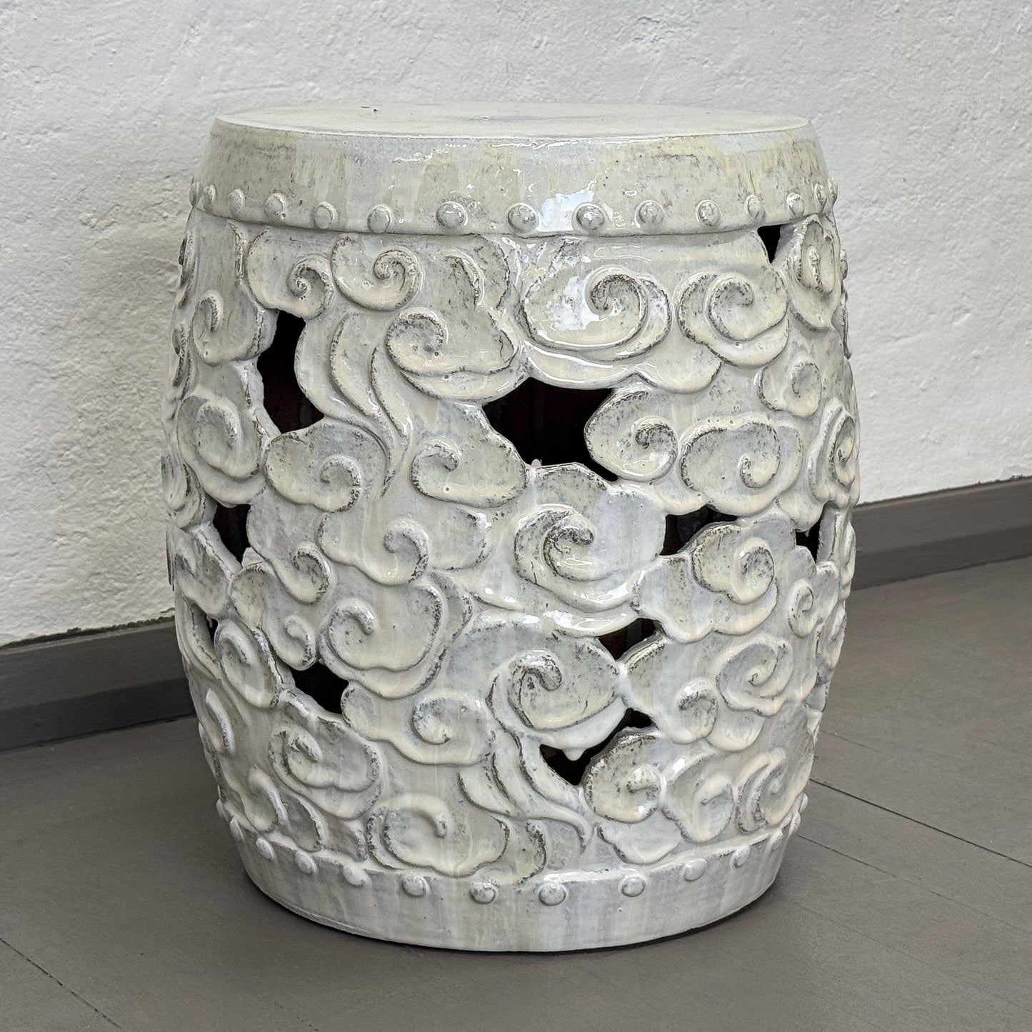 Decorative concrete stool with geometric pattern on a gray floor.