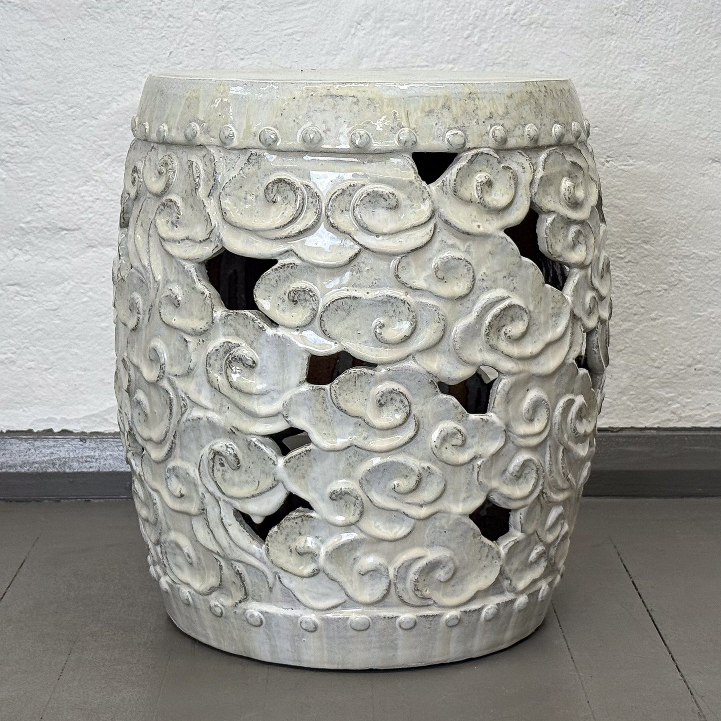 Decorative concrete stool with geometric pattern on a gray floor.