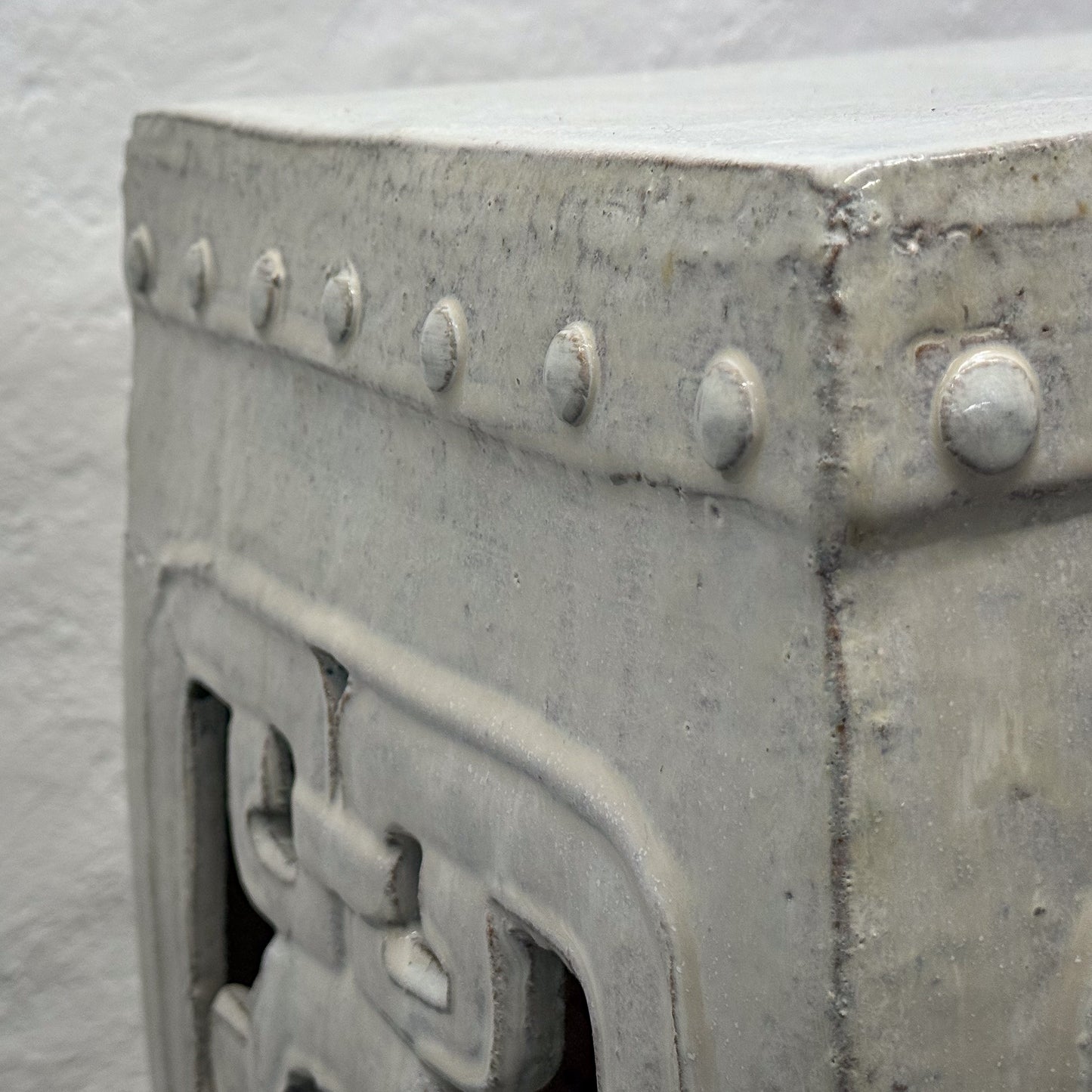 Close-up of a metallic object with rivets and intricate design on a white background