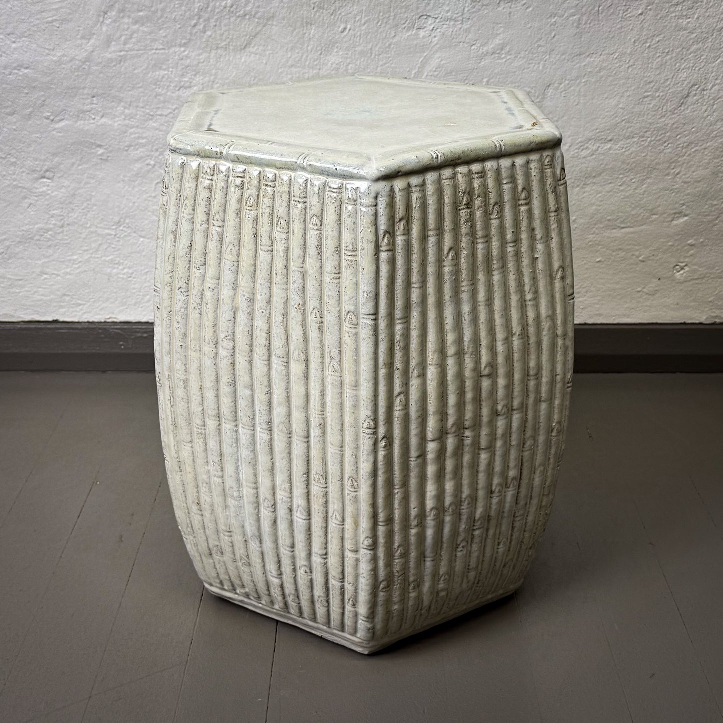 Textured white stool against a plain wall