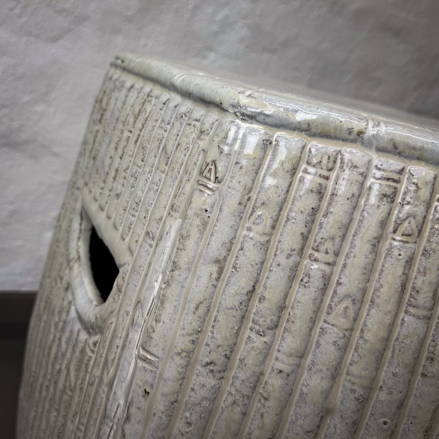 Close-up of a textured ceramic vase with geometric patterns on a gray background