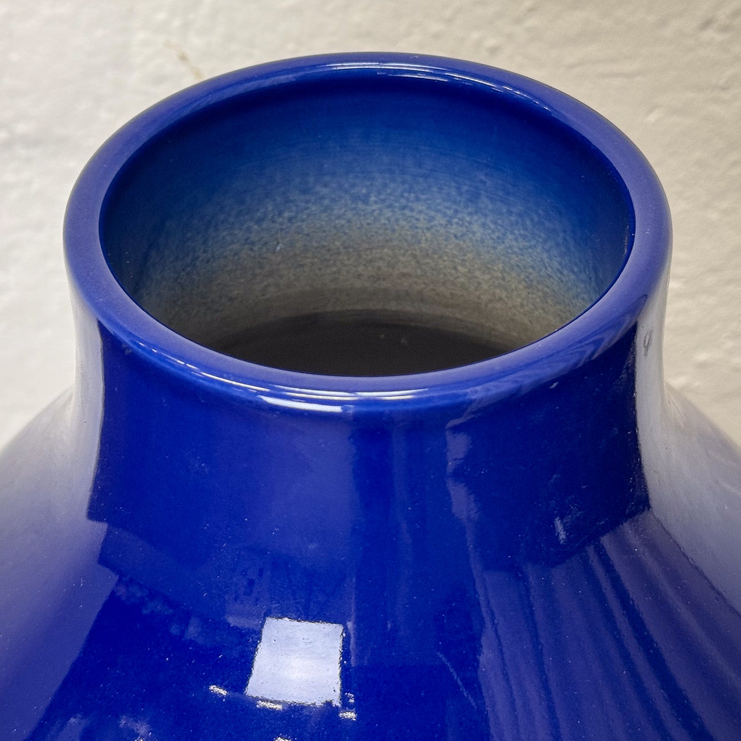 Close-up of a blue ceramic vase with a textured surface on a white background