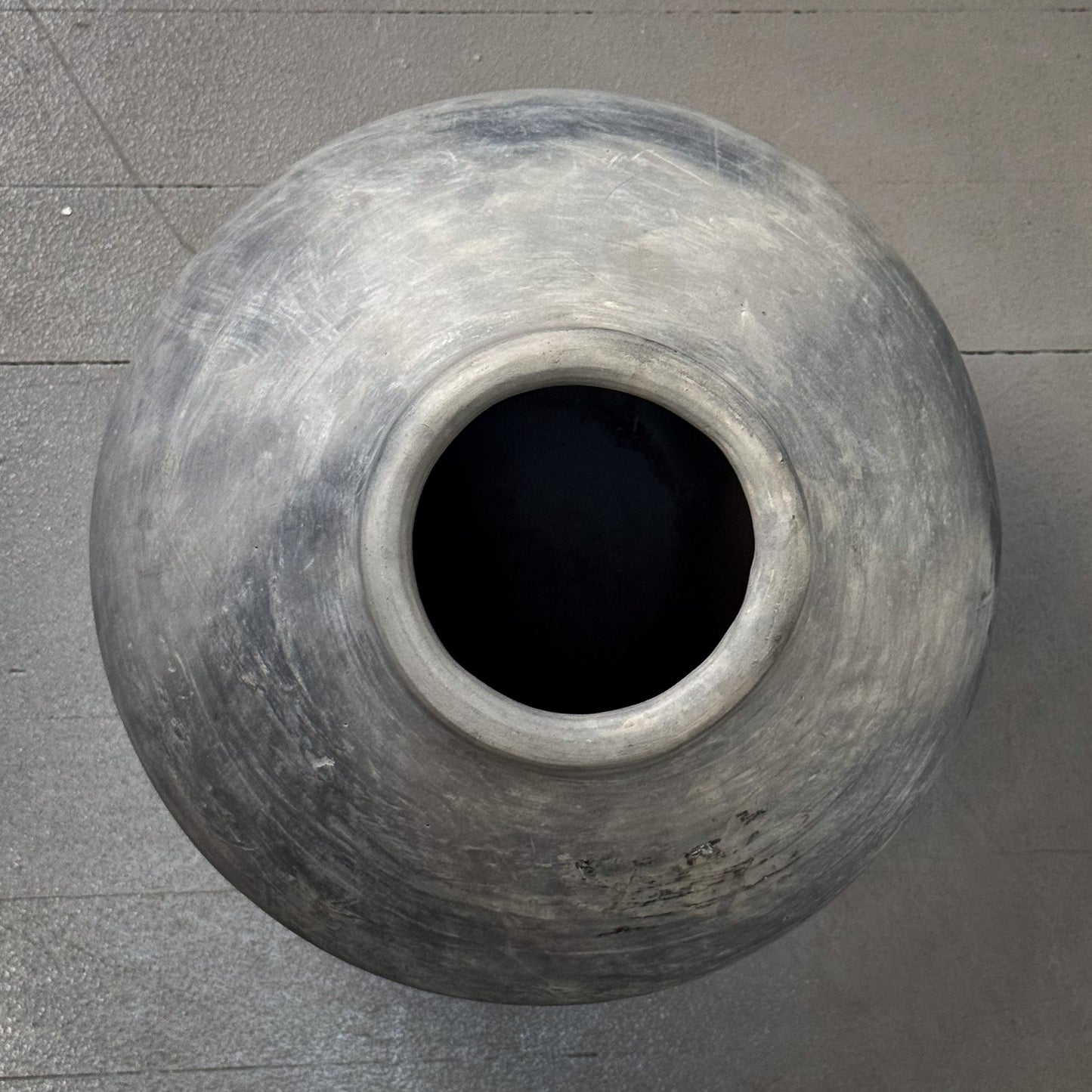 Large gray clay pot on a gray concrete floor